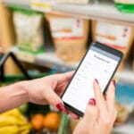 Female Customer Using Mobile Phone In Supermarket