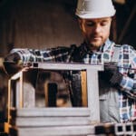 Workman wearing har hat with measuring ruler at factory