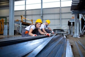 Industrial workers working in factory hall with metal.