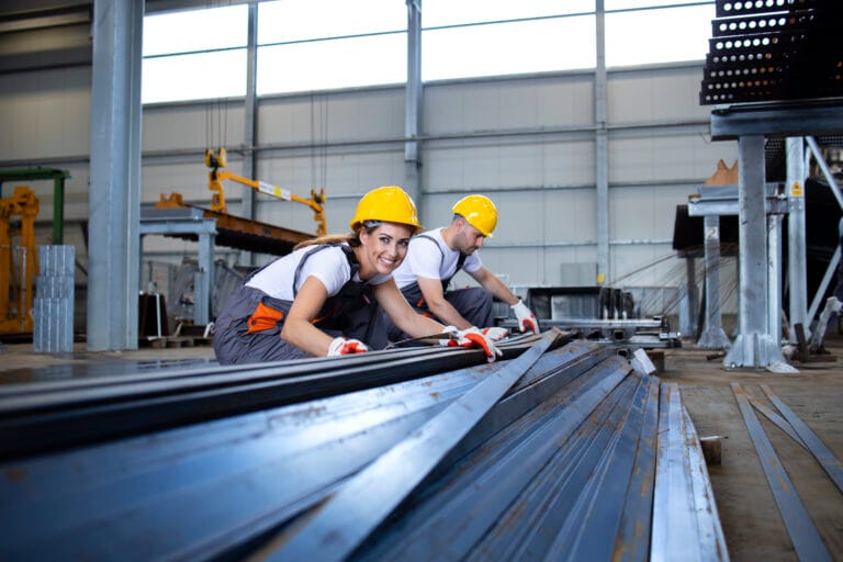 Industrial workers working in factory hall with metal.